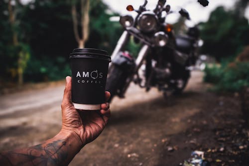 Man Hand Holding Coffee Cup and with Motorbike behind