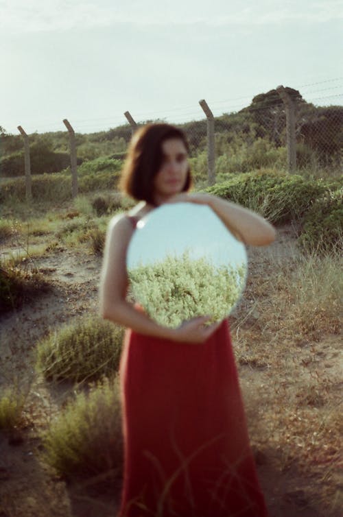 Woman Holding Mirror on Wasteland