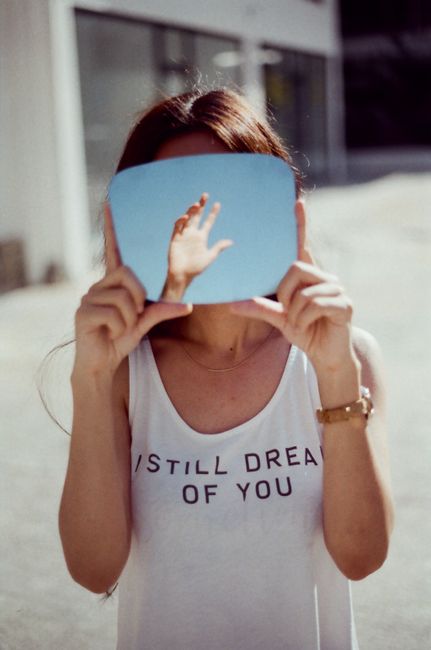 Creative photo of a woman holding a mirror reflecting a sky and hand. Conceptual and intriguing.