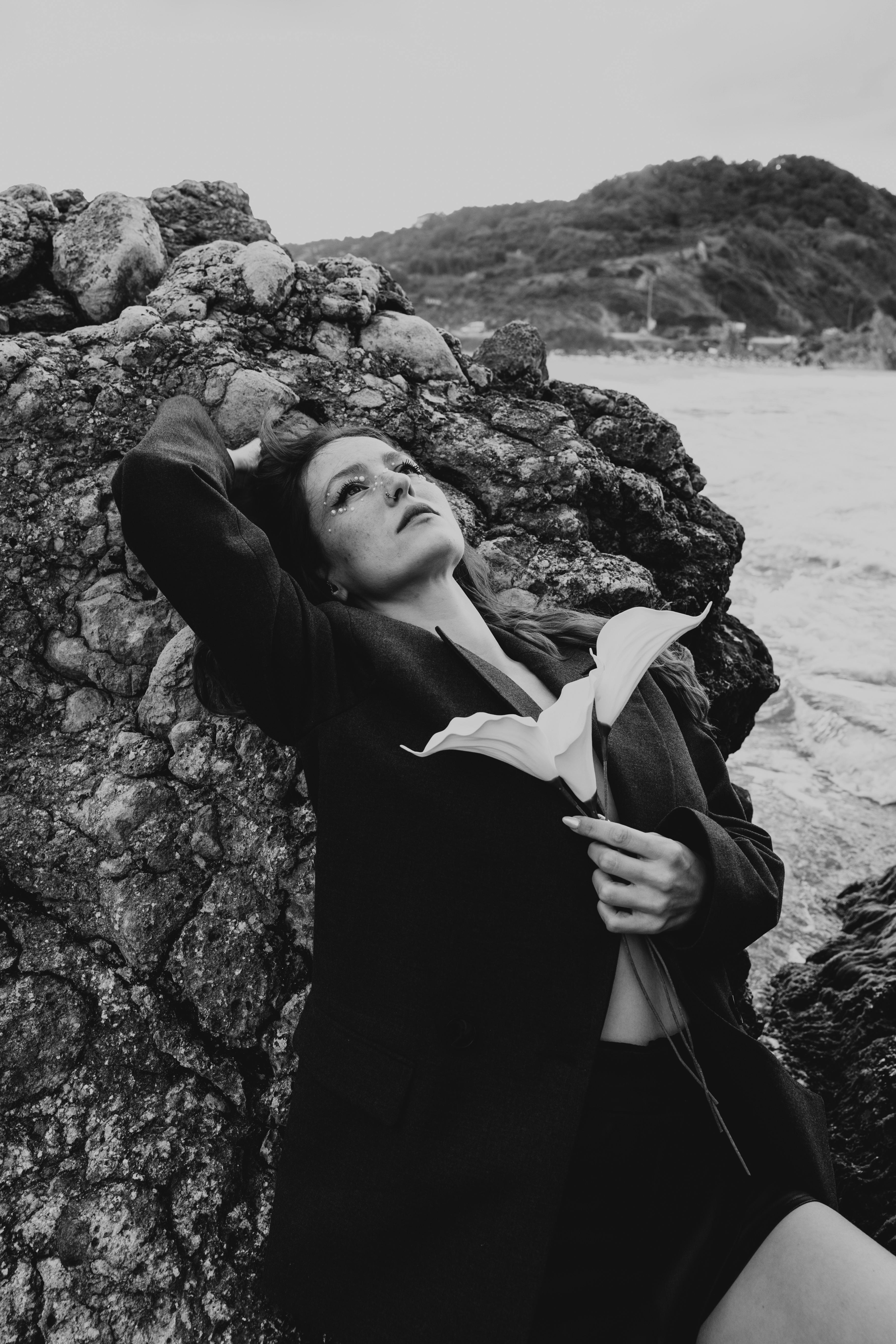 a woman laying on the rocks with her hand on her head