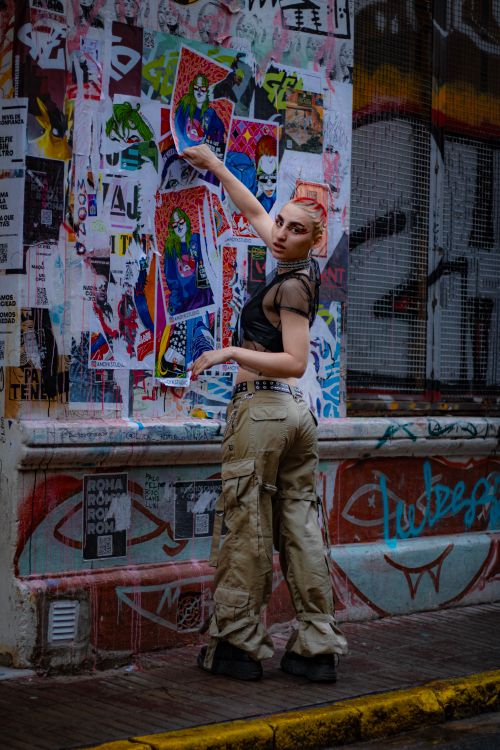Free Portrait of a woman with edgy style in a graffiti-laden urban alley, showcasing vibrant street art. Stock Photo