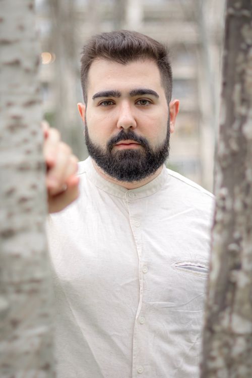 Free A fashionable man with a beard posing outdoors in a natural setting. Stock Photo