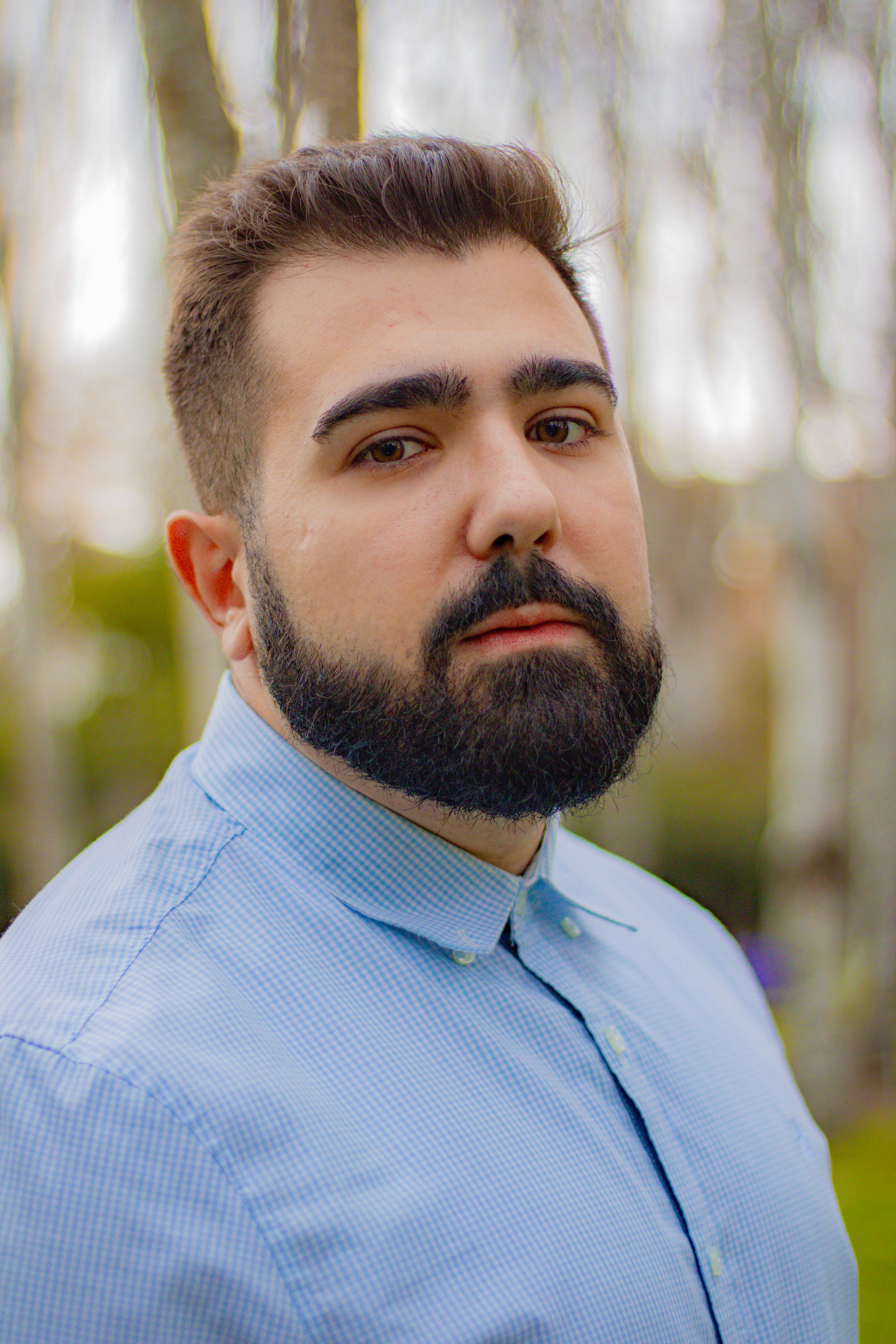 Close-up portrait of a bearded man in a blue shirt with a natural outdoor background, Buenos Aires.