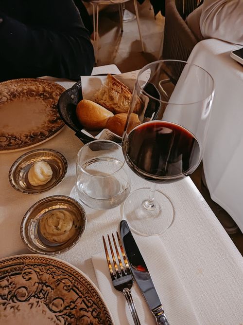 Free A sophisticated dining table setup featuring a glass of red wine, bread, and elegant tableware. Stock Photo
