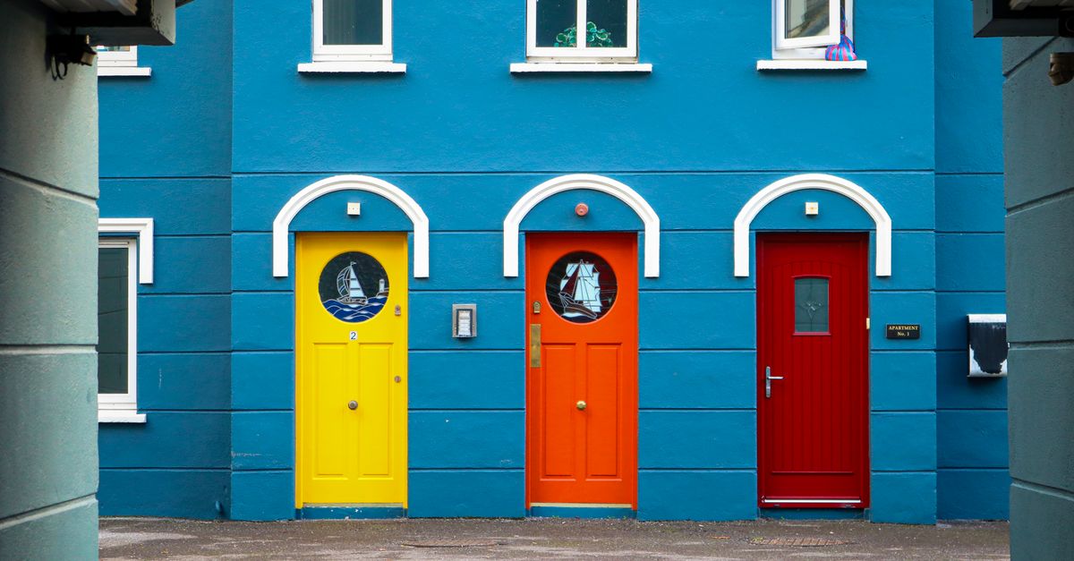 Vibrant blue building with yellow, orange, and red doors in Cobh, Ireland.