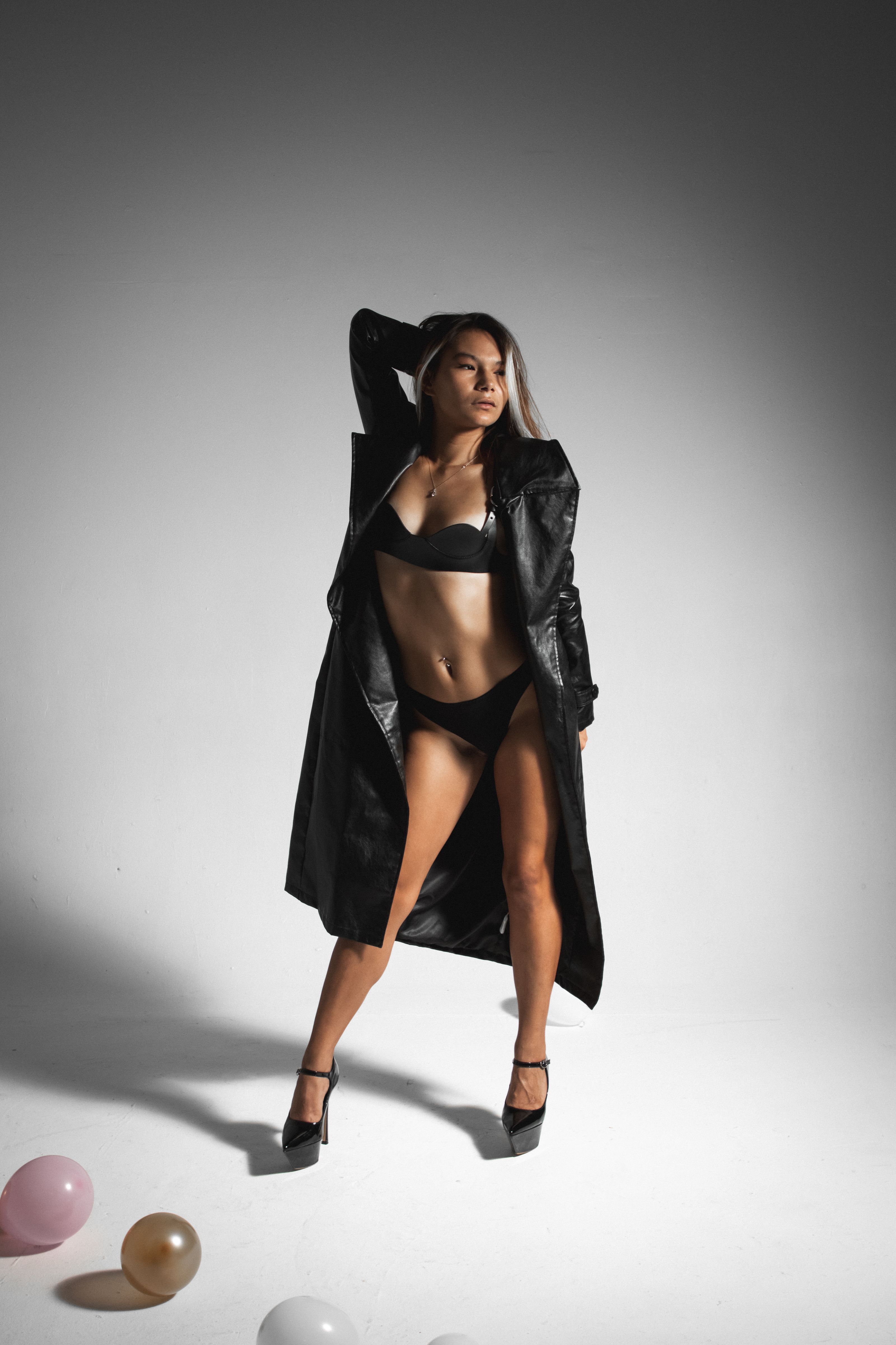 Impressionante foto de estúdio de uma modelo confiante em lingerie e casaco de couro.