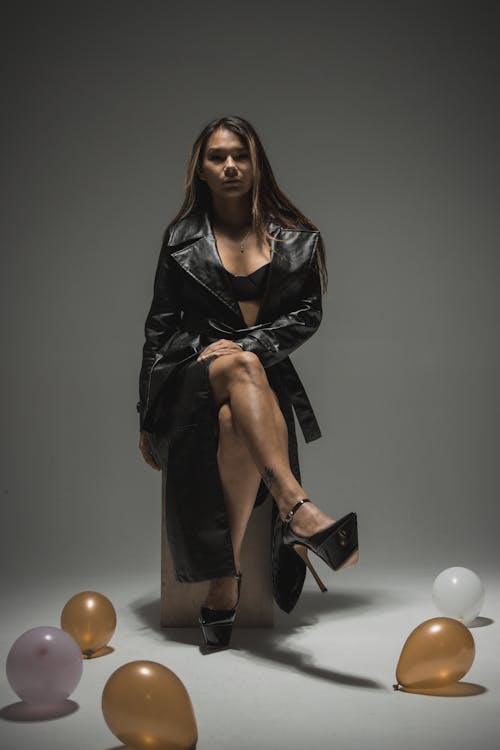 Woman in a Black Bra and Leather Coat Sitting among Balloons 
