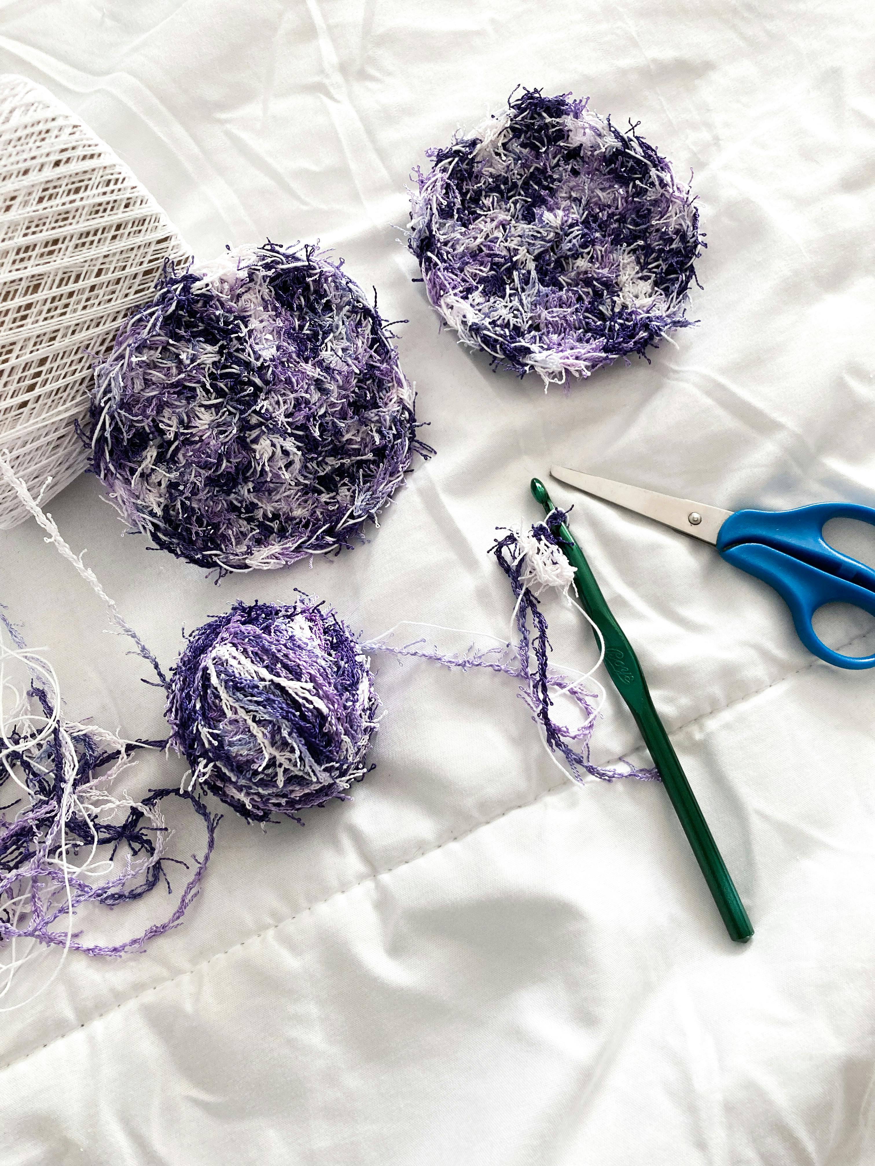 Colorful crochet scrubbies and yarn with scissors on a white background, ideal for DIY projects.