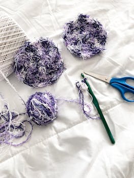 Colorful crochet scrubbies and yarn with scissors on a white background, ideal for DIY projects.