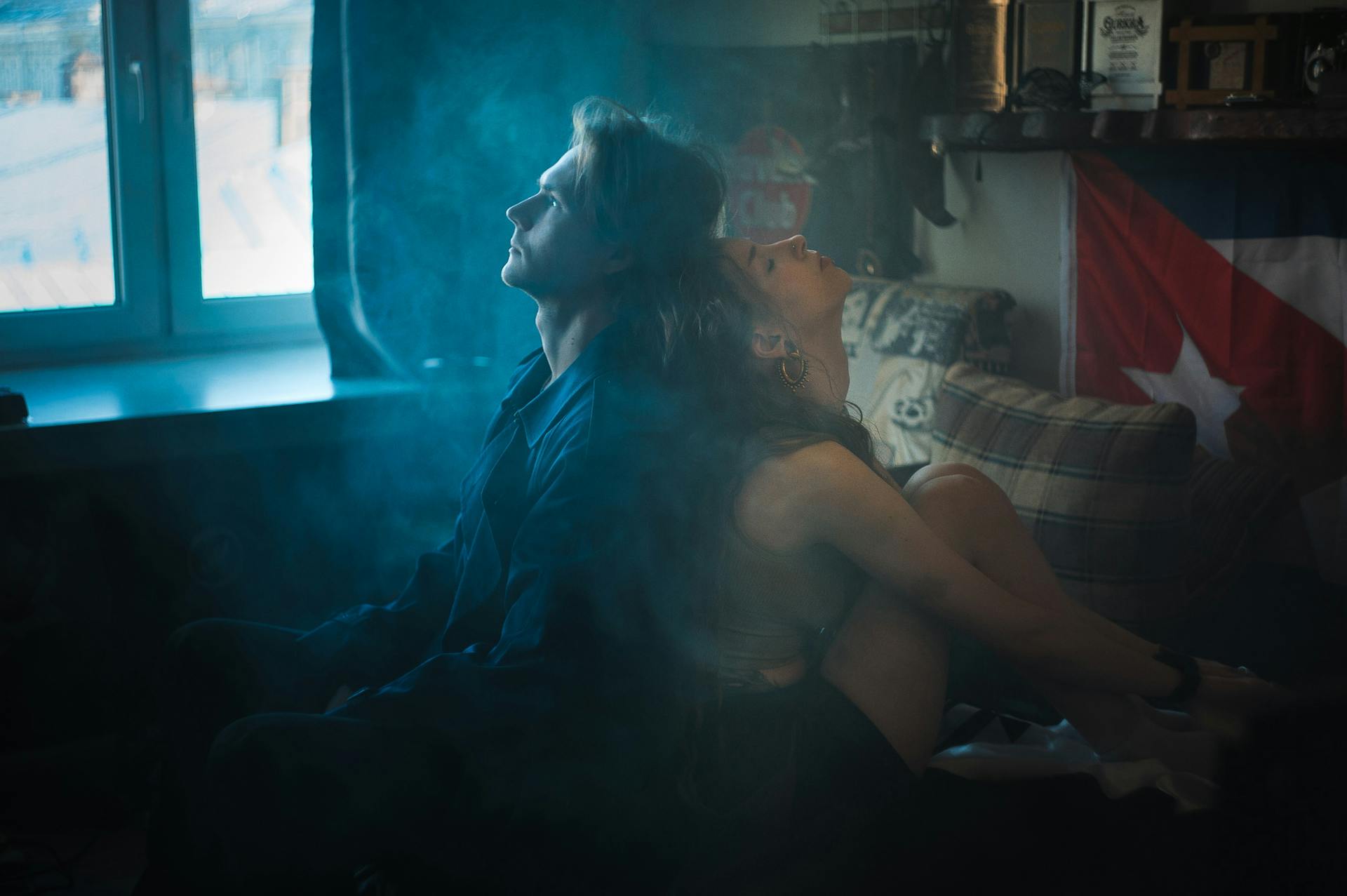 Couple Sitting Back to Back on a Bed in Smoky Room