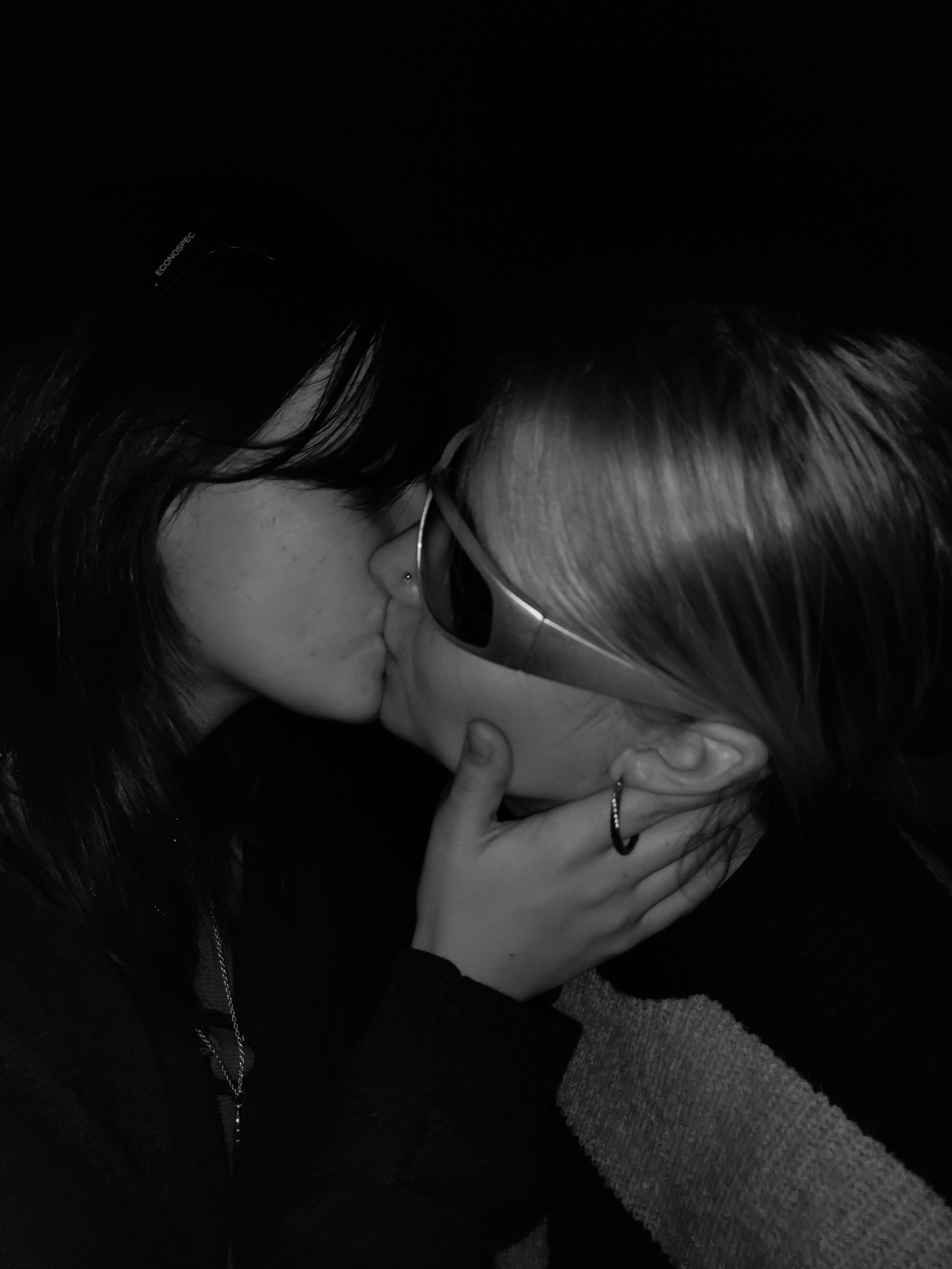 Black and white portrait of two women sharing an intimate kiss, symbolizing love and unity.