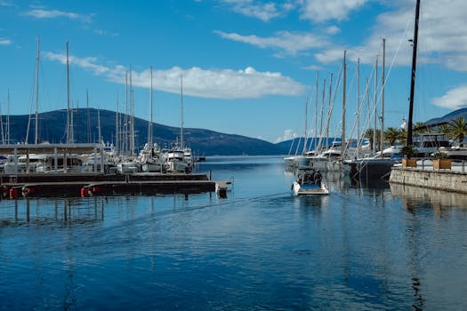 Scenic view of a marina with sailboats under blue skies, ideal for travel and nature themes.