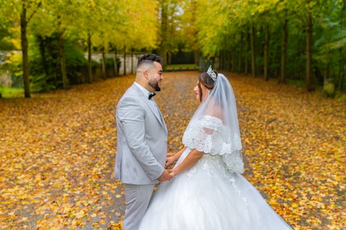 Bride and Groom Standing in a Park and Holding Hands 