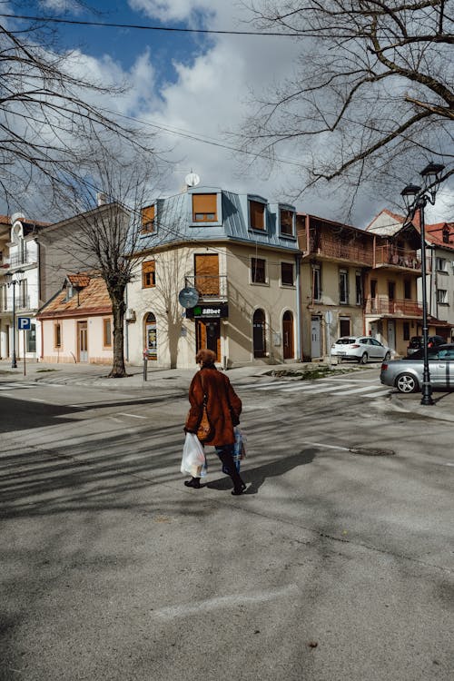 A Woman Walking with Bags on the Street in City 