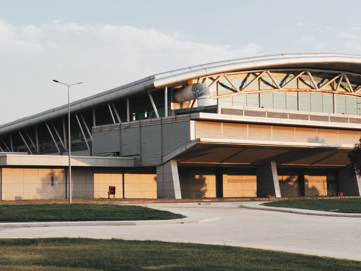 Exterior of a contemporary airport terminal building with a curved roof, illustrative of modern terminal expansion