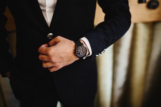 Close-up of a man in a black suit, showcasing a stylish wristwatch. Perfect for fashion and business themes.