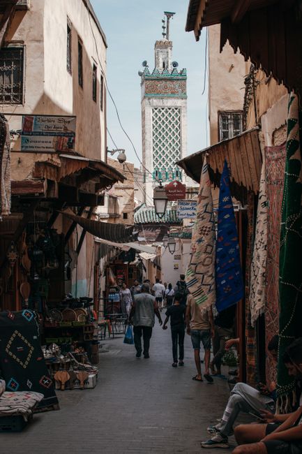Explore the bustling narrow alley of a Moroccan bazaar with shops and vibrant textiles.