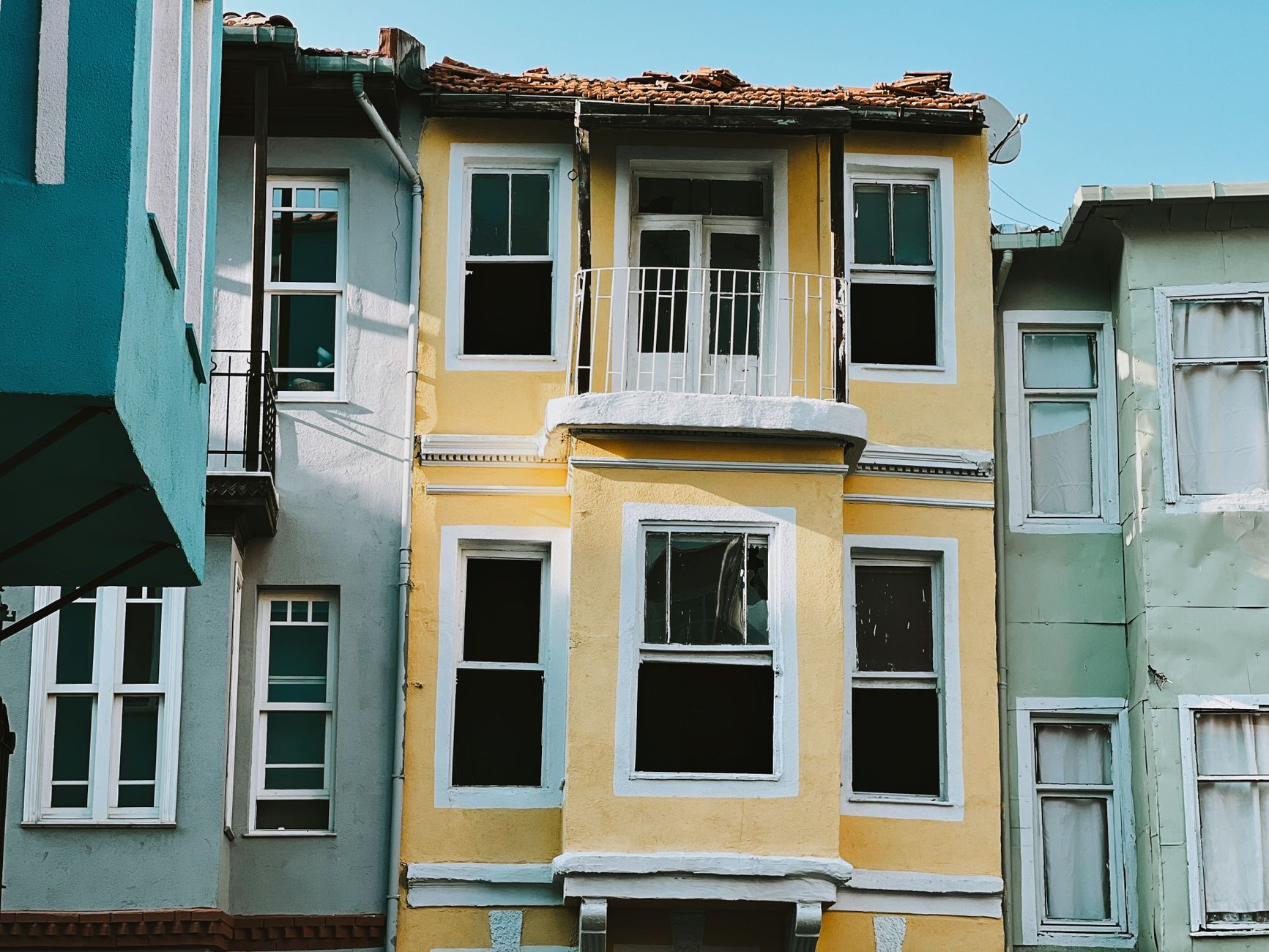 Minneapolis Townhouse Exterior Painting Cost in 2026 2 Vivid urban townhouse facades showcasing architectural diversity with balconies and windows in a vibrant city setting.
