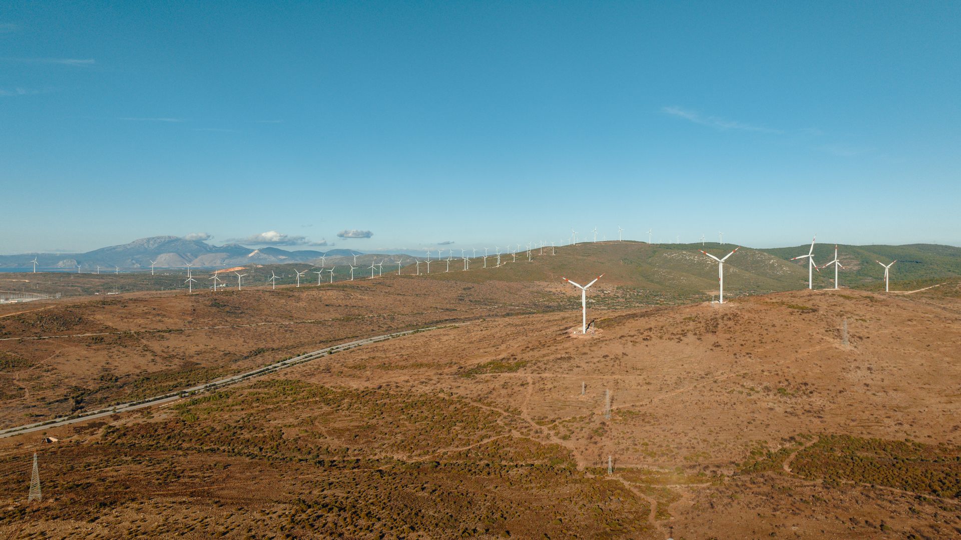 Aerial shot of a wind farm in Çeşme, Türkiye, showcasing renewable energy in a desert landscape.