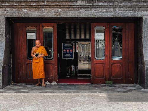 Tibetan Monk Standing under Building Entrance