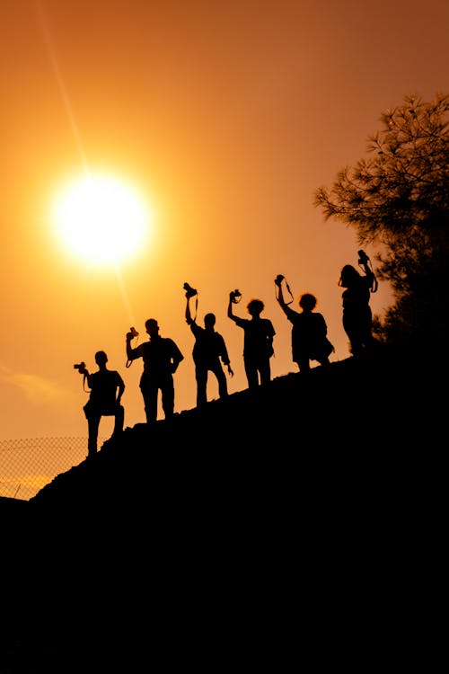 Silhouettes of People with Cameras on a Hill 
