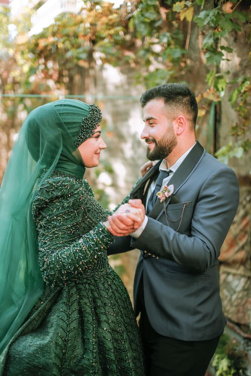 Free Newlyweds embrace in a verdant garden setting, exuding elegance. Stock Photo