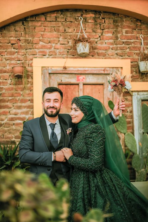 Bride and Green Dress and Headscarf Posing with her Groom in Elegant Suit Free Stock Photo Bride and Green Dress and Headscarf Posing with her Groom in Elegant Suit Free Stock Photo