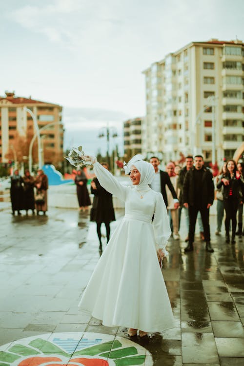 Smiling Bride in Wedding Dress in City and People Standing behind