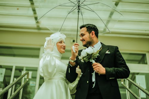 Bride and Groom Standing under an Umbrella 