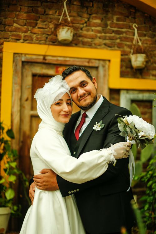 Free A happy couple embraces outdoors, featuring a bride in a white dress and a groom in a suit. Stock Photo