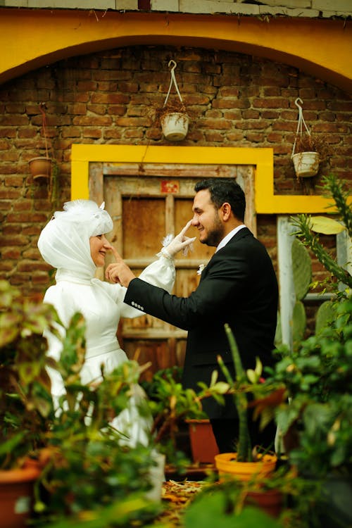 Bride and Groom Standing in a Greenhouse and Smiling 