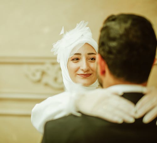 Smiling Woman in Wedding Dress Hugging Man