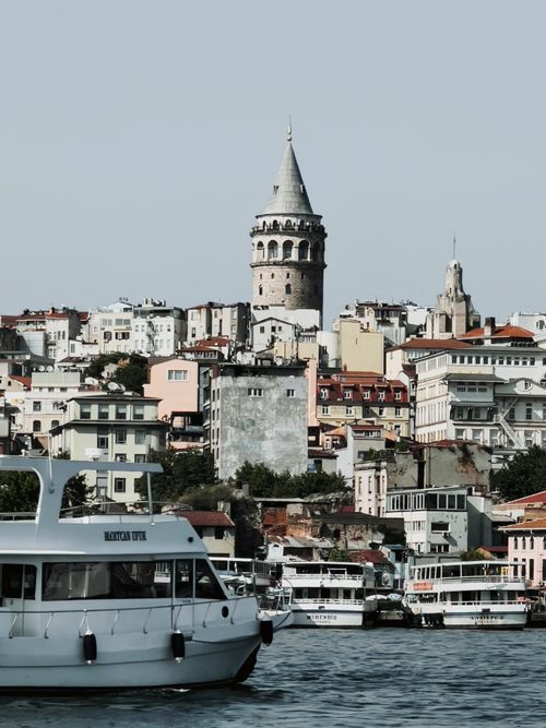 Free View of Galata Tower and vibrant Istanbul cityscape with boats along the shore, perfect for travel and architecture enthusiasts. Stock Photo