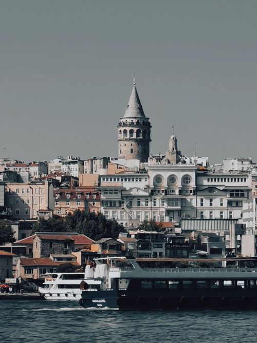 Free Scenic view of Galata Tower amidst Istanbul's urban landscape with a ferry in the foreground. Stock Photo