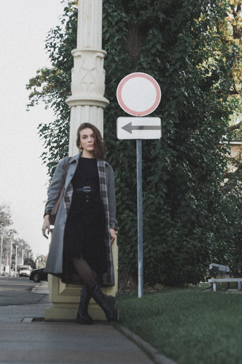 Woman in Coat Standing near Road Sign