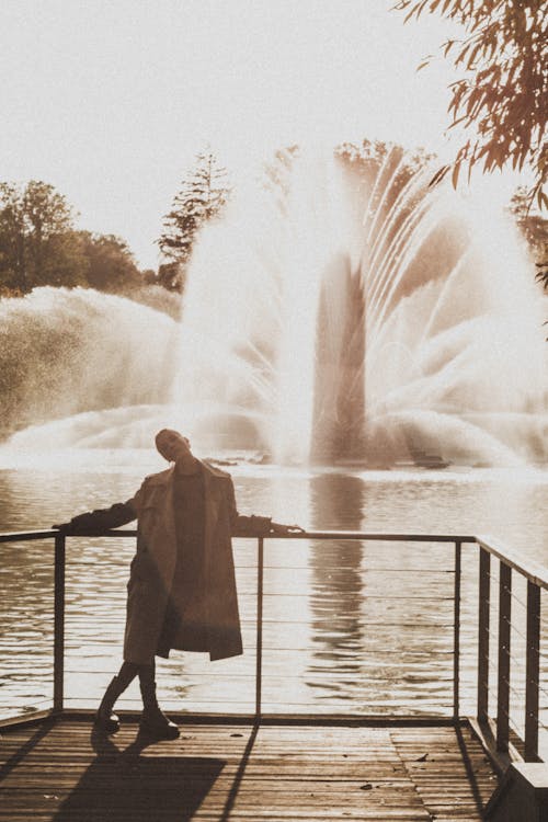 Woman in Coat Posing with Fountain behind