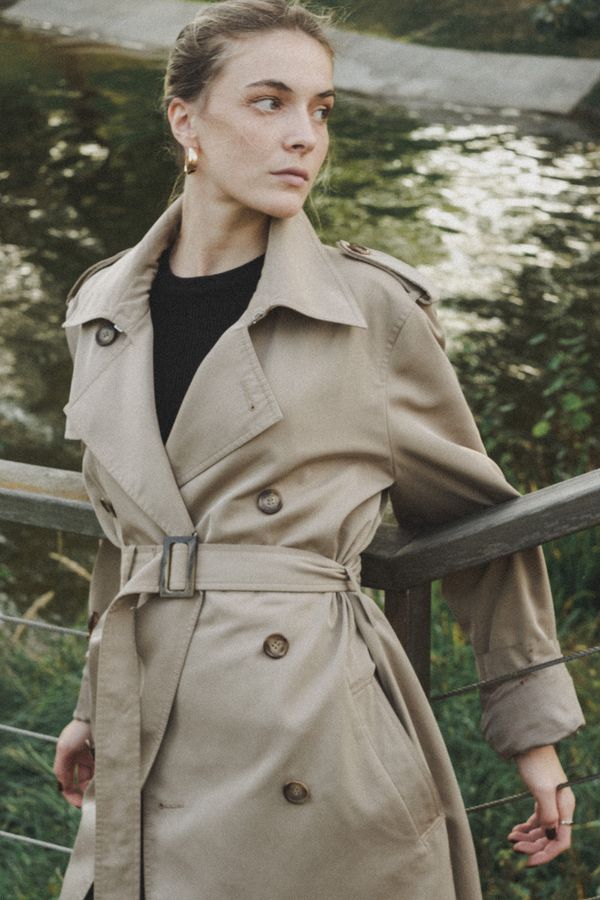 Woman in trench coat leaning on a railing