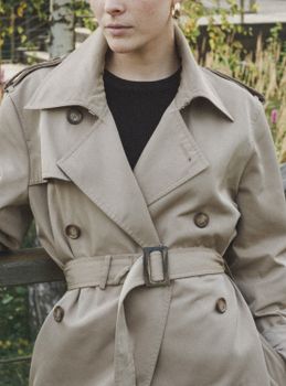 Close-up of a woman in a stylish trench coat, showcasing fall fashion outdoors.