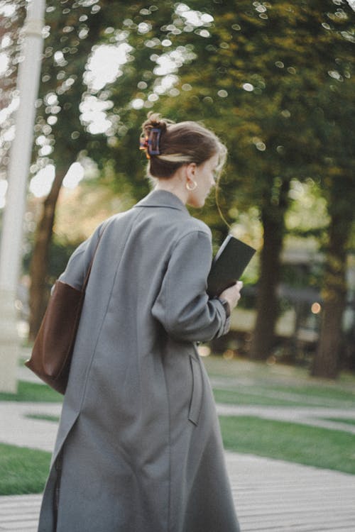 Woman in a Coat Walking in a Park 