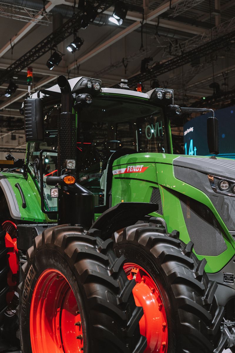 Close-up of a modern green tractor displayed indoors at a technology exhibition