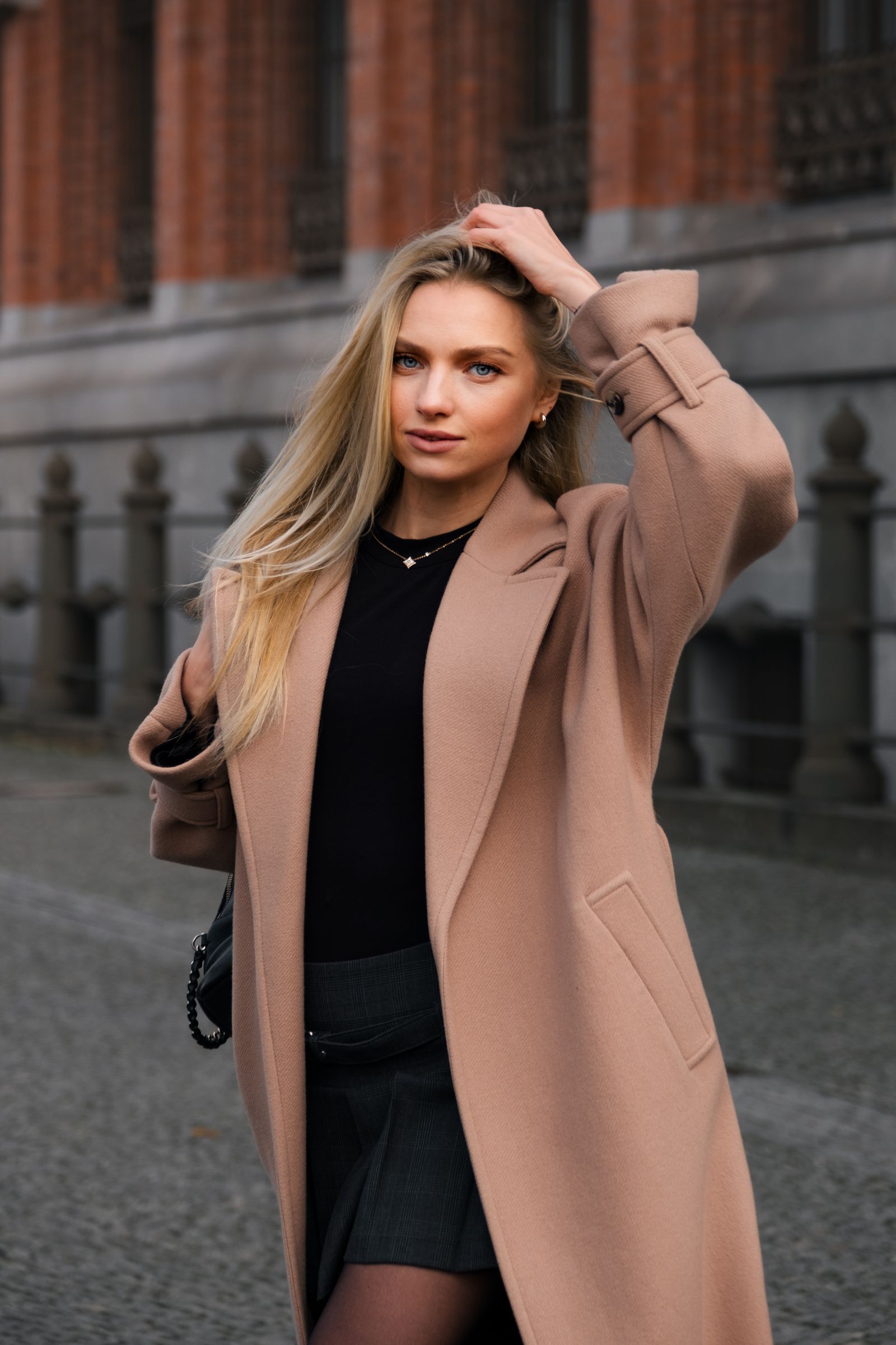 Woman in affordable camel coat over sweater dress
