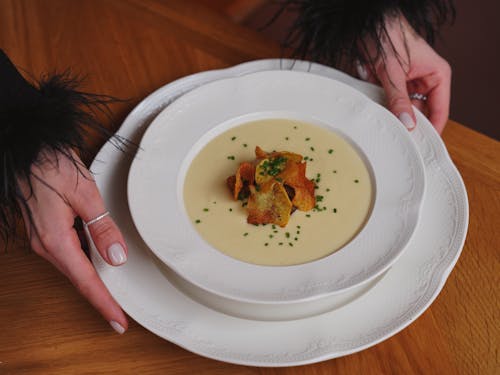 Woman Holding a Plate with Creamy Soup 