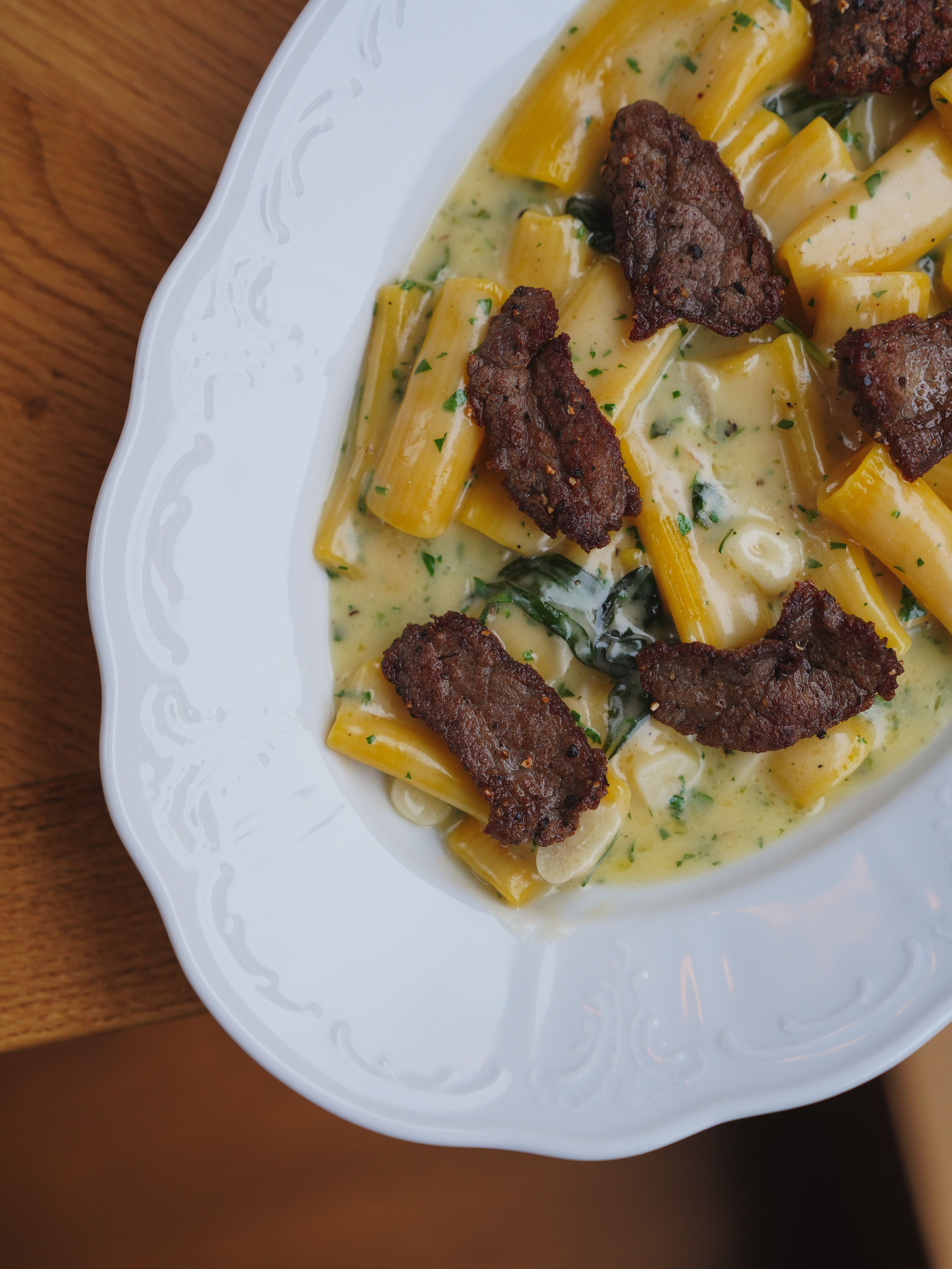 Creamy rigatoni topped with slices of deeply seared beef and fresh herbs