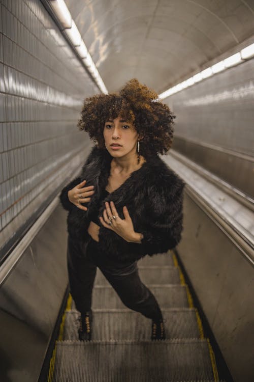 Woman with Curly Hair Standing on Escalator