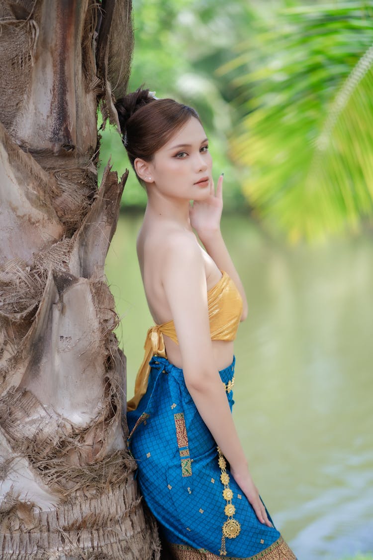 Model In A Golden Tie Back Tube Top And A Printed Blue Skirt On The Riverbank