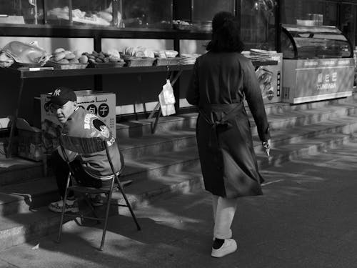 A Woman Passing a Street Vendor