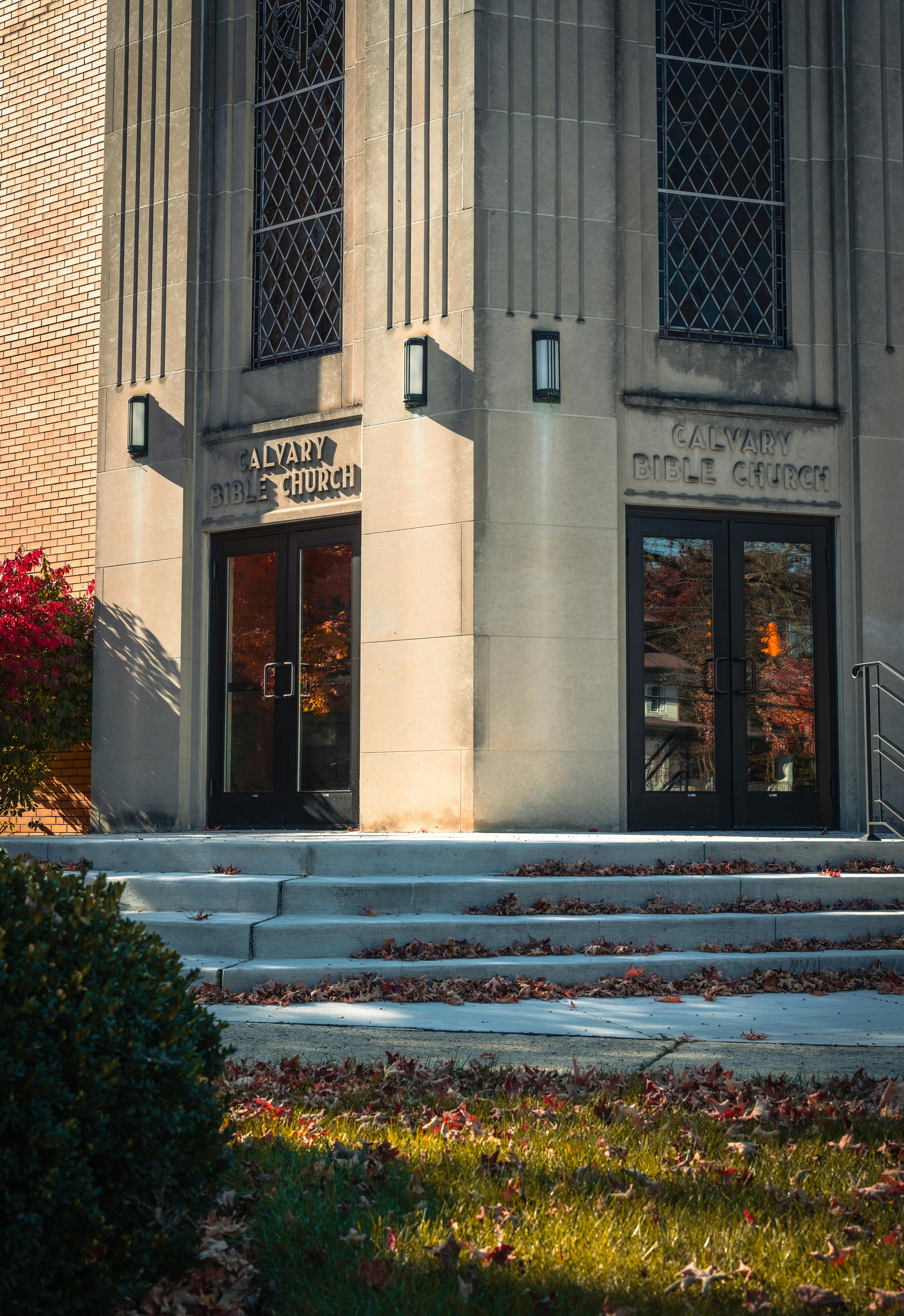 Vertical shot of Calvary Bible Church entrance with steps covered in autumn leaves.