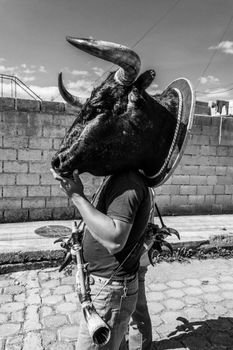 Black and white photo of a man wearing a bull costume on a cobbled street in Quito, Ecuador.