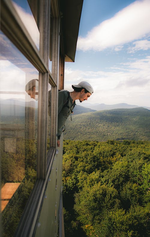 Man Looking Down through Window of Tower in Forest