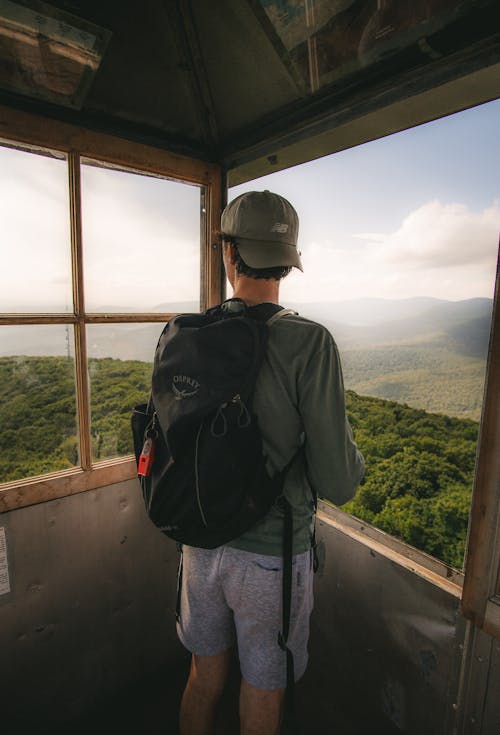 Man with Backpack Standing in Tower in Forest